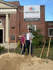 Bank employees standing outside of a bank donated building for the Easthampton Public Library holding shovels. 