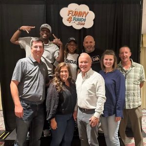 Bank employees at a comedy show standing on a stage and posing for a photo.