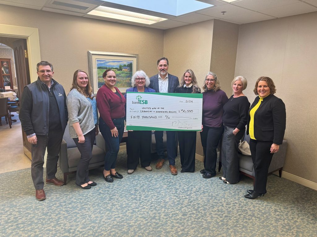 bank employees holding a large checking donation for United Way. 